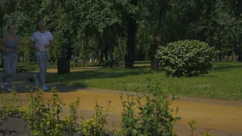 Aged Couple Running in Park and Smiling at Each Other, Doing Sport, Slowmotion