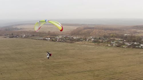 Flying parachutist near the village on a foggy day