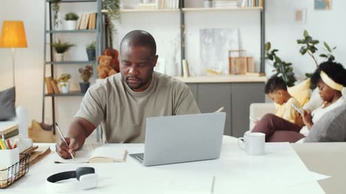 Man Working on Laptop, Family Relaxing at Home
