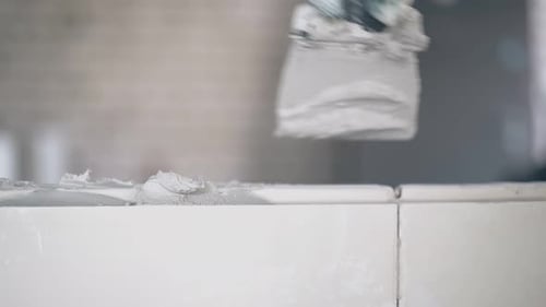 Applying Gray Grout Between White Tiles Close Up