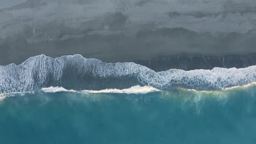 Aerial view of ocean wave splashes into the sand coast