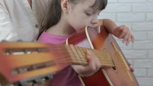 Girl Learning Guitar with Adult