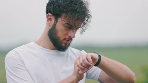 Young Man Checks Fitness Tracker Outdoors