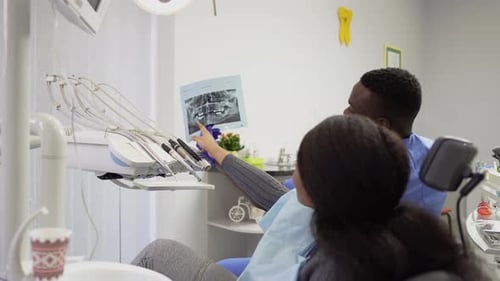 Side Angle View of Female African Lady Patient Speaking with Her Doctor Dentist Handsome African Man