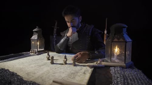 Man Planning Strategy with Map and Miniature Figures