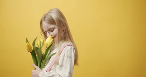 Little Girl with Tulips on Yellow Background