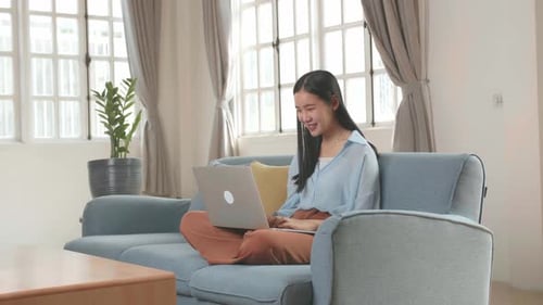 Woman Works on Laptop Computer on Blue Couch
