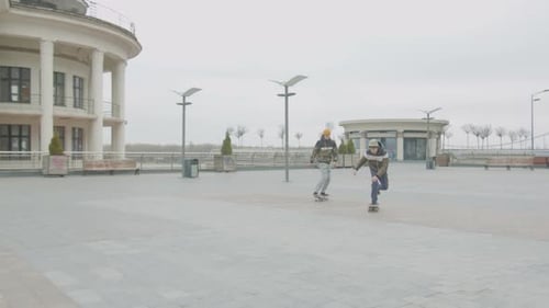 Young Adults Skateboarding in Urban Plaza on Overcast Day