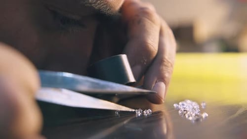 Jeweler Looks at Shiny Gems at Wooden Table Close View