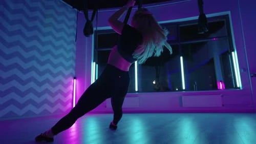 Woman Practicing Aerial Yoga in Neon Studio