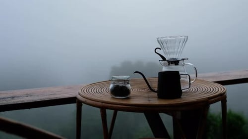 A set of drip coffee equipment on wooden table at the terrace on foggy day