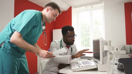 Doctors Collaborate Viewing Monitor In Hospital Office