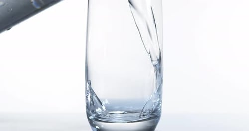 900035 Se vierte agua en un vaso sobre un fondo blanco, Cámara lenta 4K