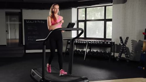Woman athlete running on treadmill, doing cardio workout in gym