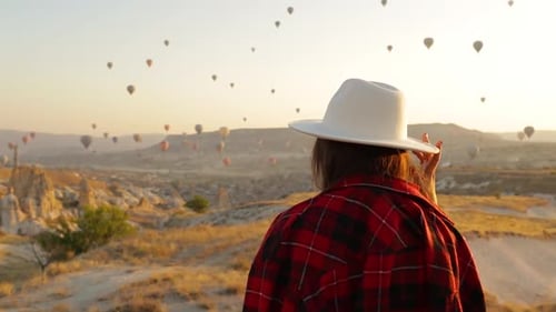 Woman Watching Hot Air Balloons Over Cappadocia at Sunrise
