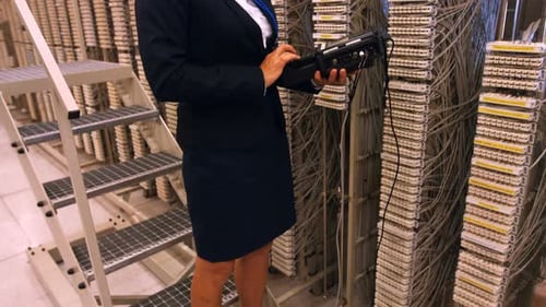 Woman Operates Telecom Equipment in a Wiring Room