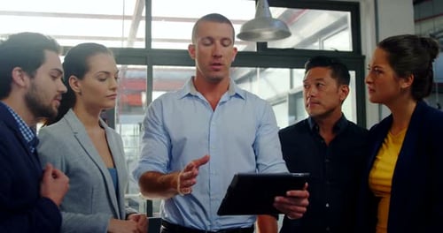 Colleagues Discussing Work on Tablet in Modern Office