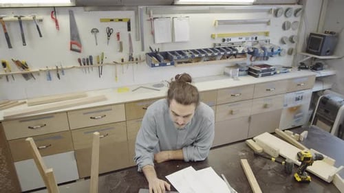 Caucasian Carpenter Working with Laptop and Furniture Drafts at Workshop