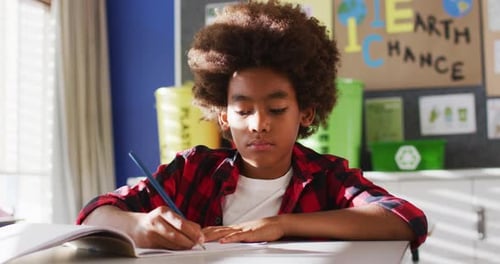 Child Writing at Desk in School Classroom