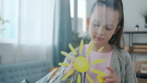Zeitlupenporträt eines kreativen Kindes, das Sonne auf Glas malt, drinnen in der Wohnung