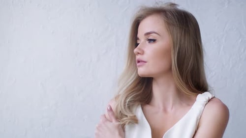 Beautiful Blonde Woman in White Dress Posing Indoors