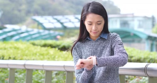 Woman Using Smart Watch in City Park
