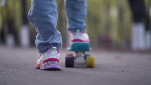 Close Up Legs Riding on Skateboard in Motion of Asphalt in Park