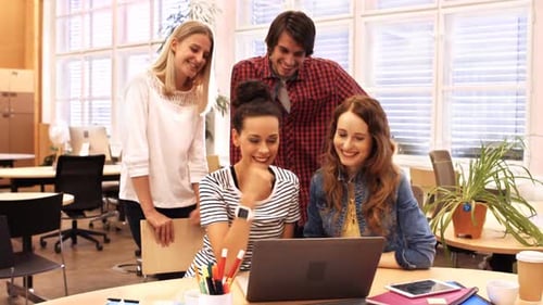 Group of business executives discussing over laptop at their desk