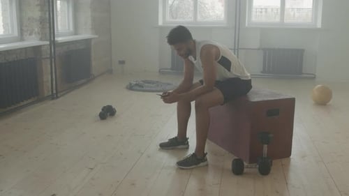 Young Adult Using Phone After Workout in Gym