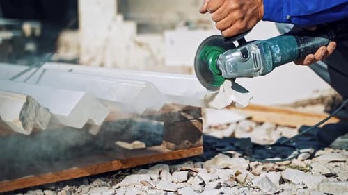 Arbeiter beim Schneiden von Steinblock. Arbeiter mit einem kleinen Winkelschleifer schneidet einen Granit