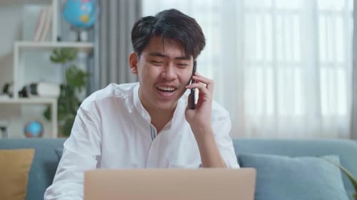 Young Adult Working on Laptop and Talking on Phone