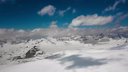 Air Flight Through Mountain Clouds Over Beautiful Snowcapped Peaks of Mountains and Glaciers