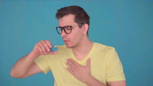 Middle-aged Man in Glasses and T-shirt Asthma Attack,uses Spray