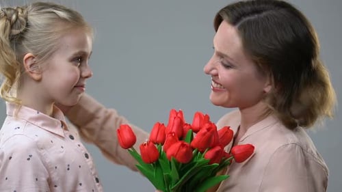 Little Girl Gives Tulips to Smiling Woman