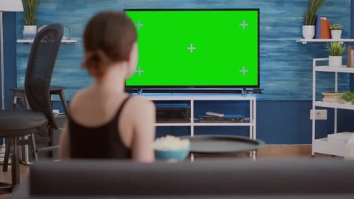 Young Woman Picking Up Snack Bowl and Eating Popcorn While Watching Favourite Tv Show on Green