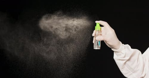 Hand Sprays Fine Mist from Bottle on Black