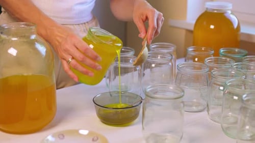 Adult Pouring Yellow Liquid into Jars