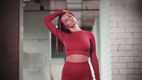 Young Woman in Red Sports Suit Doing Fitness Exercises in the Gym Warming Up Her Neck