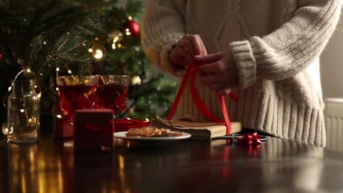 Woman Tying Christmas Gift Ribbon at Home