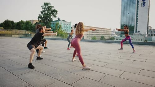 Woman in Sportswear Training a Group of Athletes