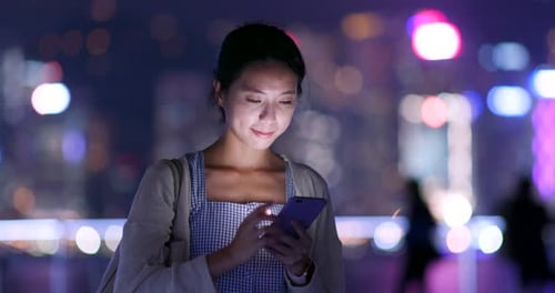 Woman Using Smartphone in City at Night