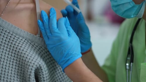 Closeup Sticking Medical Patch on Shoulder After Coronavirus Vaccination