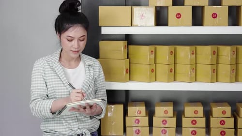 young woman entrepreneur counting parcel boxes in her own job shopping online business at home