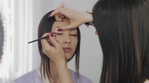 Das Gesicht des jungen asiatischen Models während des Make-up-Prozesses