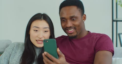 Couple Smiling Using Smartphone at Home Together