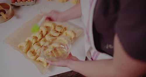 Woman Brushing Croissants with Egg