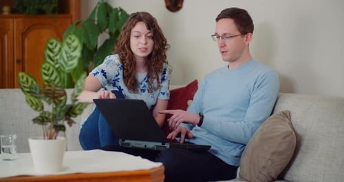 Couple Working Together on a Project While Man is Typing on Laptop