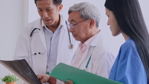 Doctors Consulting Over X-Ray in Hospital Room