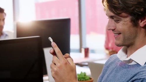 Young Man Smiling While Using Phone at Work