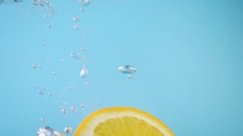 Frische Orange in Scheiben geschnitten mit ins Wasser fallenden Luftblasen